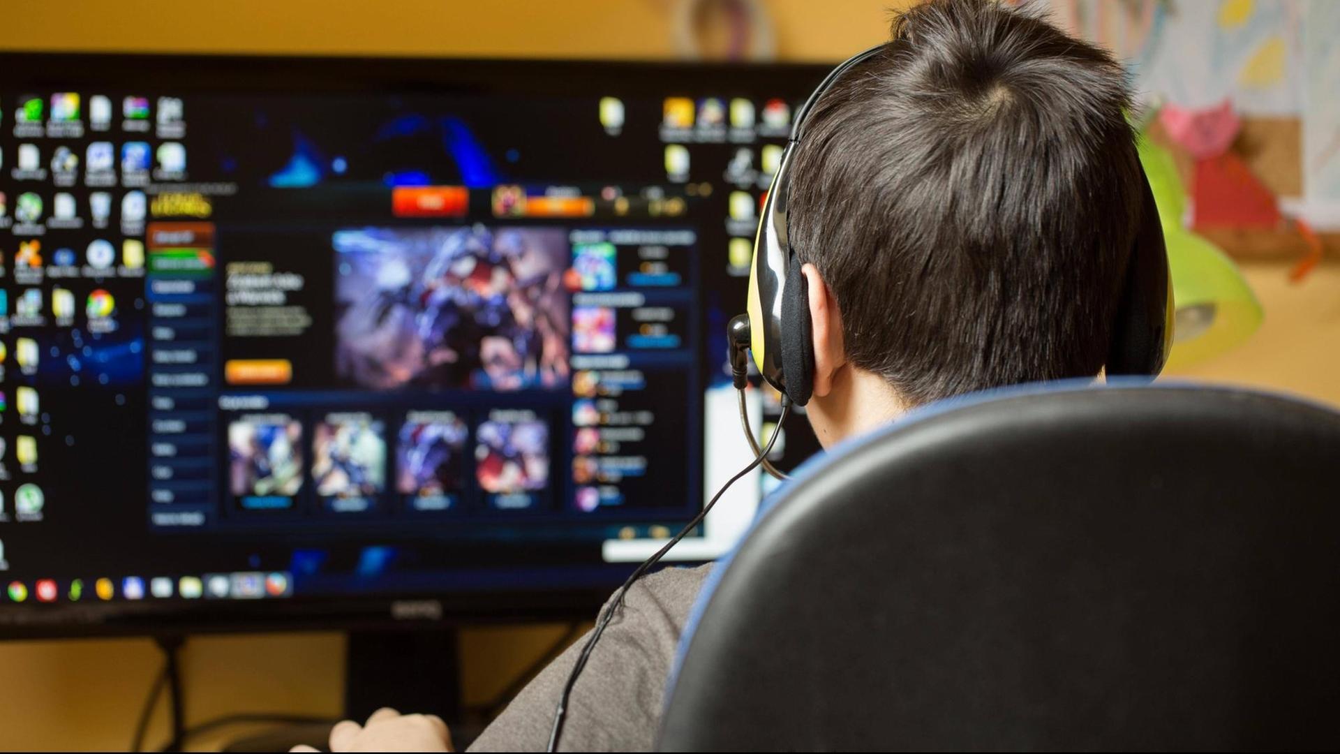 Ein Teenager sitzt mit Kopfhörern vor einem Computerbildschirm. Ein Teenager sitzt mit Kopfhörern vor einem Computerbildschirm.