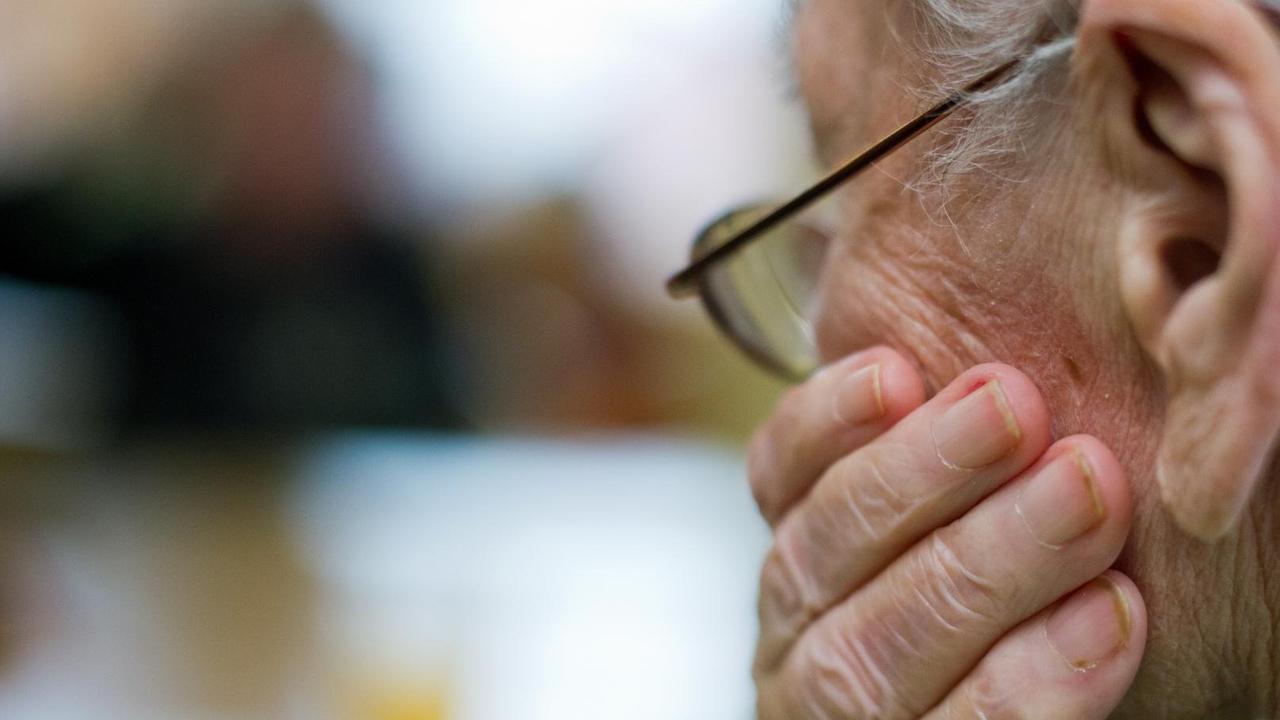 Der Hinterkopf einer alten weißhaarigen Frau, die ihren Kopf auf die linke Hand stützt. Der Hinterkopf einer alten weißhaarigen Frau, die ihren Kopf auf die linke Hand stützt.