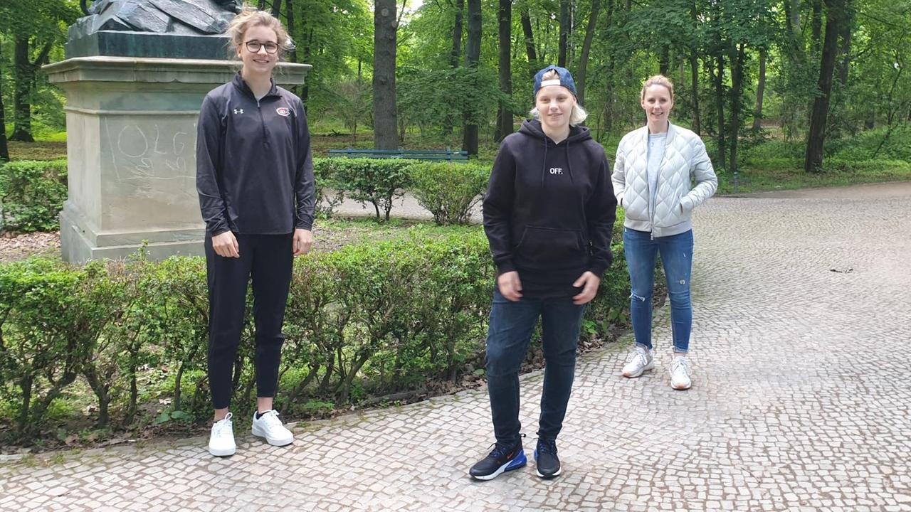 Drei Frauen stehen in ziviler Kleidung im Park und lächeln in die Kamera Drei Frauen stehen in ziviler Kleidung im Park und lächeln in die Kamera