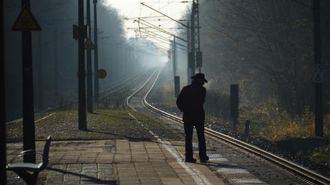 Ein Mann wartet im Morgennebel auf einen Regionalzug