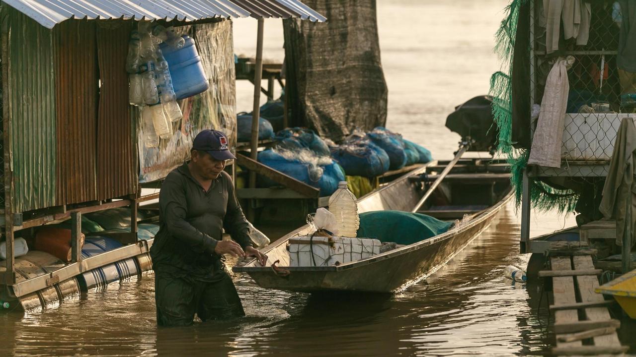 Ein Fischer legt sein Boot am Mekong, an einer schwimmenden Siedlung an.
