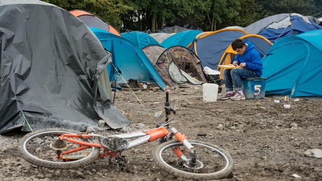 Ein Flüchtling inmitten von Zelten im Flüchtlingslager von Calais.