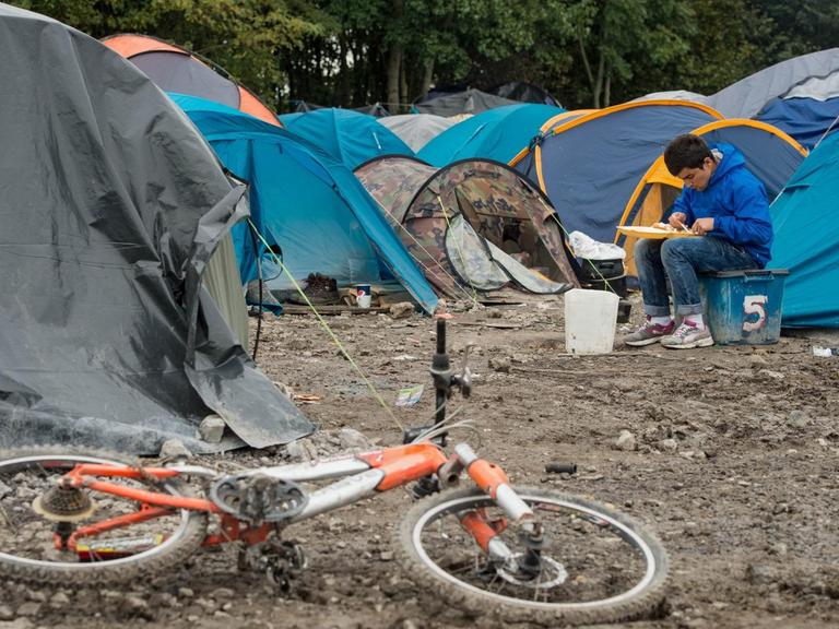 Ein Flüchtling inmitten von Zelten im Flüchtlingslager von Calais.