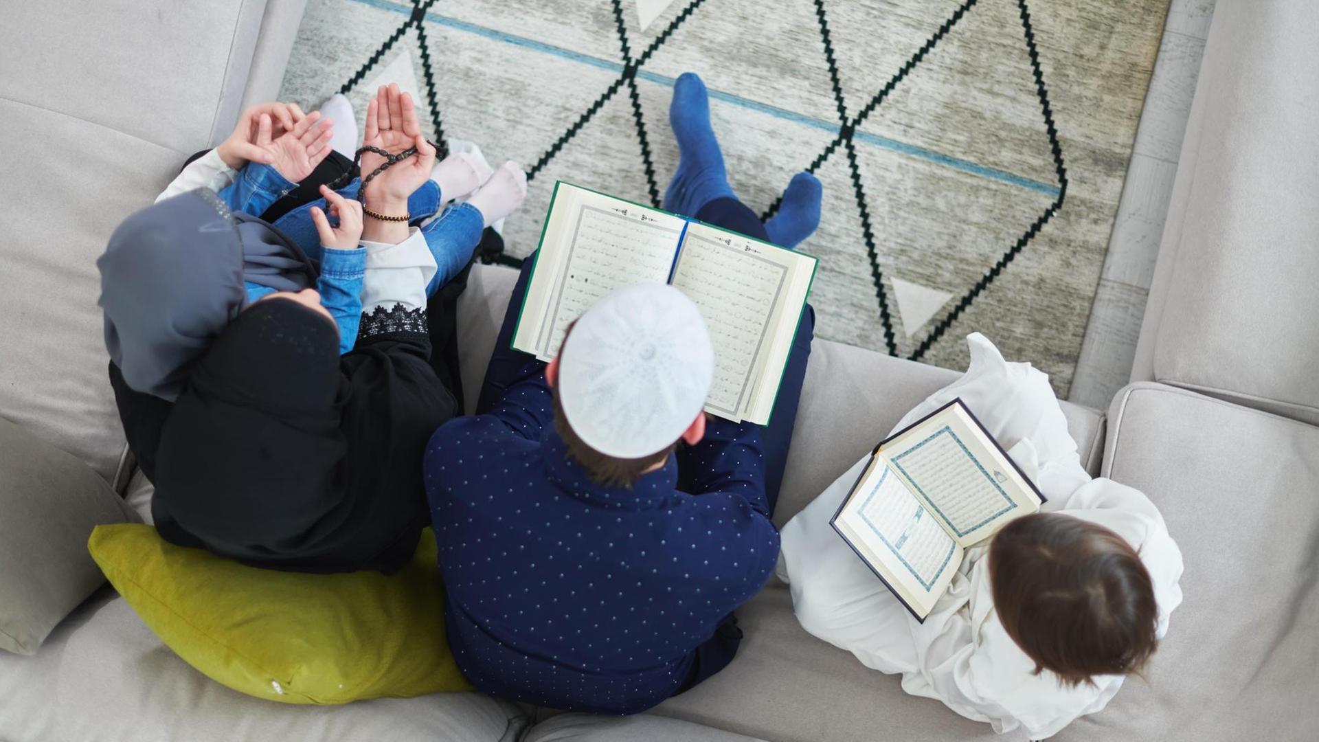 Blick von oben auf eine junge muslimische Familie, die während des Ramadan im Koran lesen. (Symbolbild) Blick von oben auf eine junge muslimische Familie, die während des Ramadan im Koran lesen. (Symbolbild)