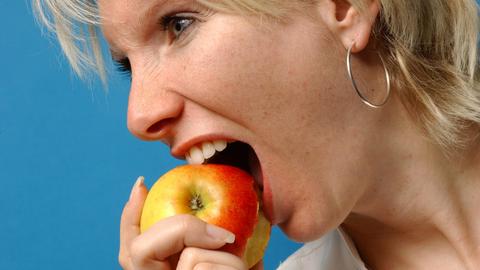 Eien Frau beißt in einen Apfel.