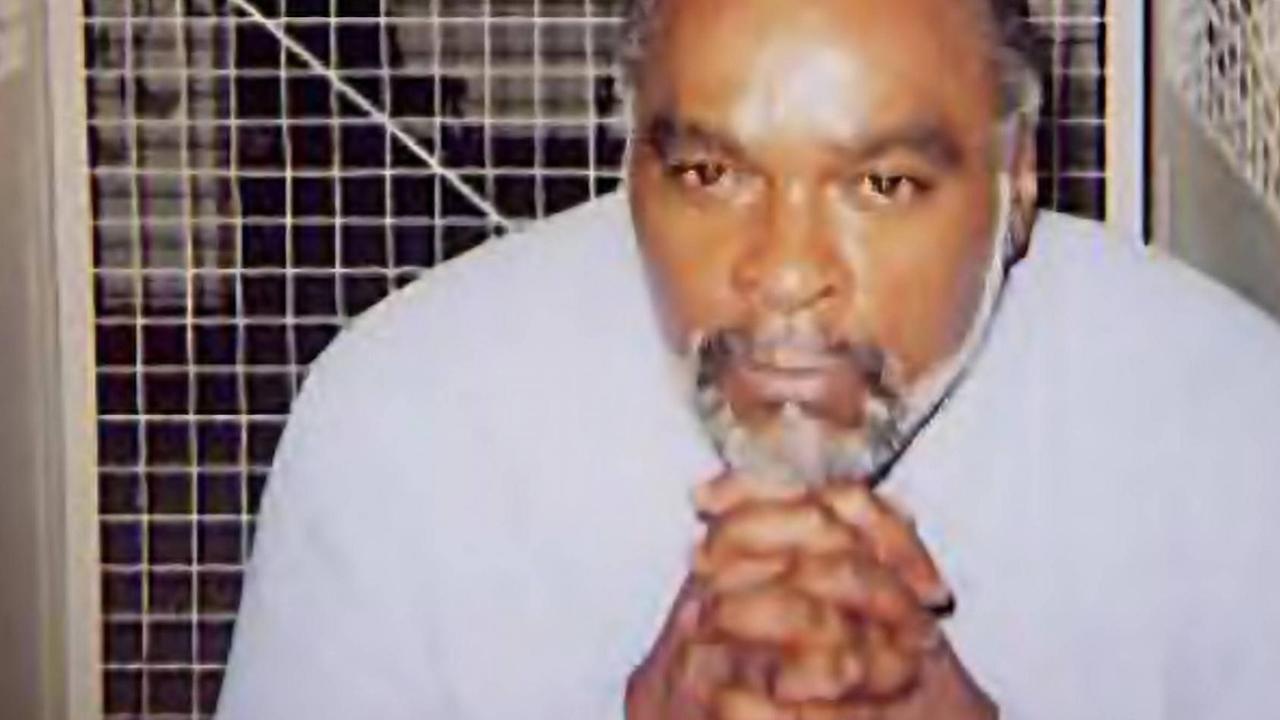 Stanley "Tookie" Williams sitzt mit gefalteten Händen in einer Gefängniszelle.