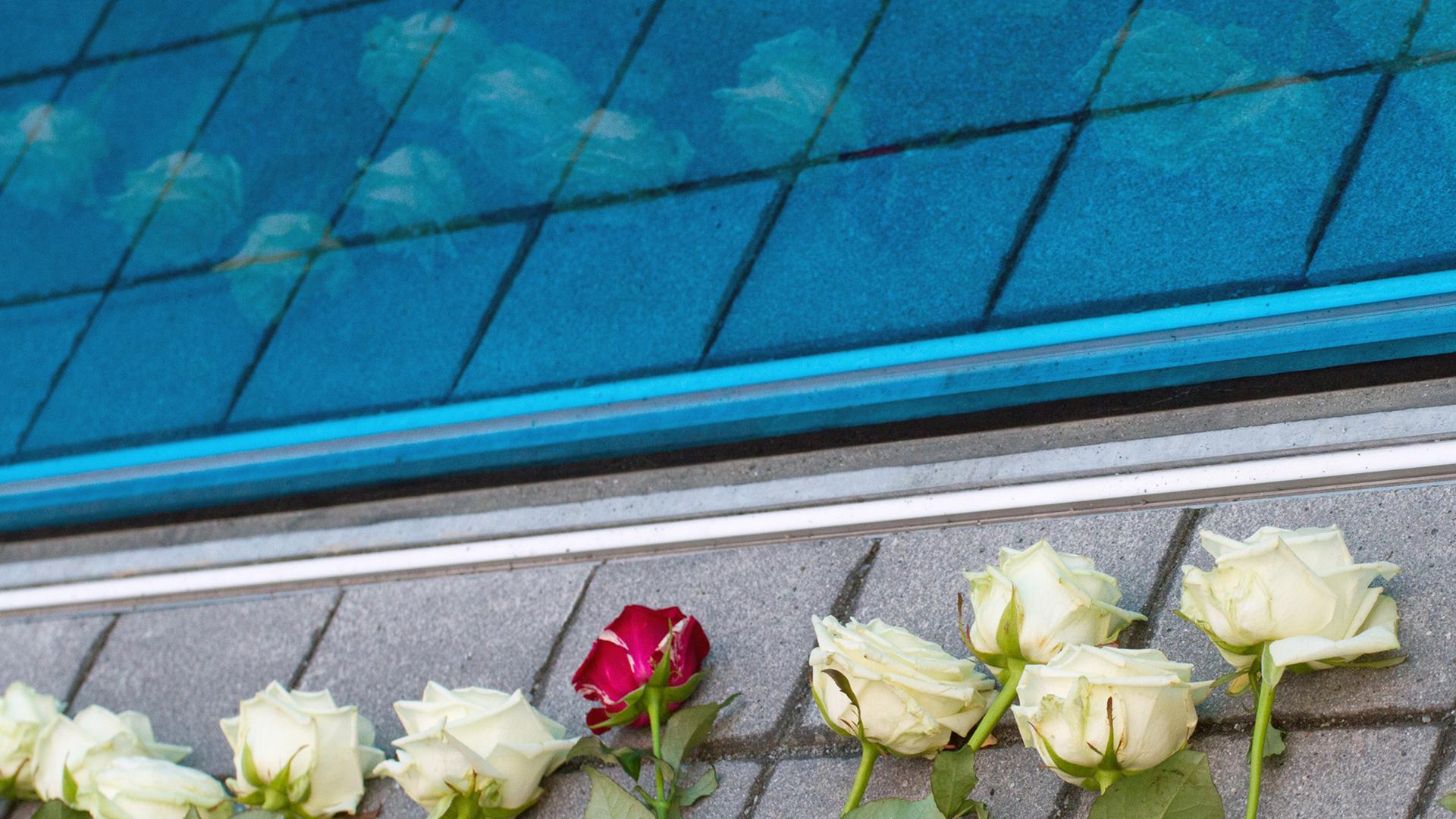 Rosen liegen an der blauen Glaswand des Mahnmals für die Opfer der nationalsozialistischen "Euthanasie-Morde". In der Berliner Tiergartenstraße Nr. 4 befand sich ab April 1940 die Zentrale der Organisation, die den Massenmord an Patienten aus Heil- und Pflegeanstalten koordinierte und durchführte.