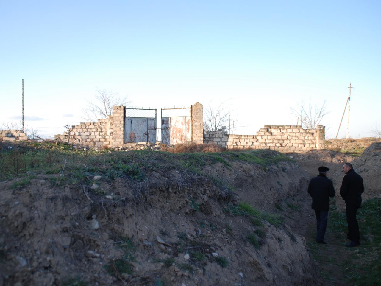 Bewohner des aserbaidschanischen Dorfs Chiragli bewegen sich am 4. Dezember 2013 zum Schutz vor armenischen Scharfschützen in Gräben. Hinter dem von Schüssen durchsiebten Tor liegen die armenischen Stellungen.