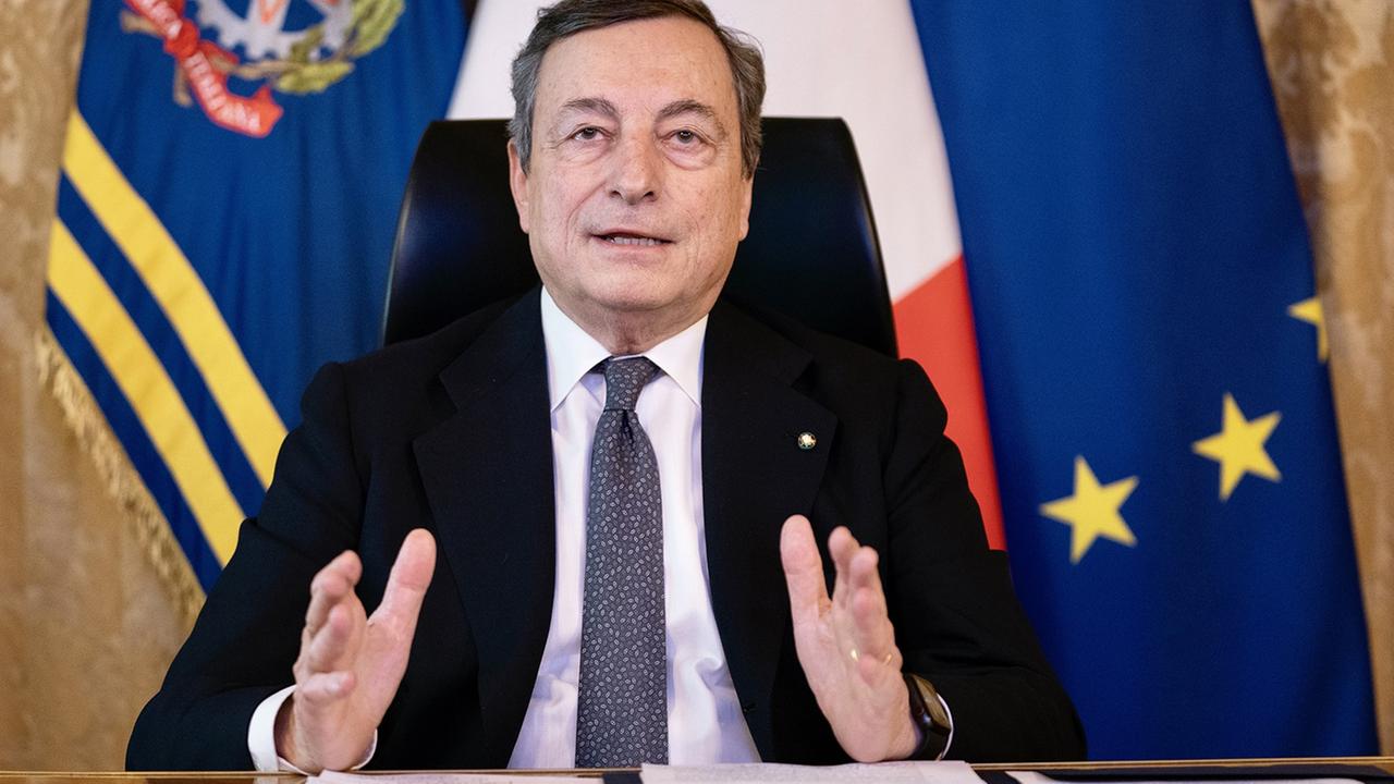 Zu sehen ist Regierungschef Mario Draghi, im Hintergrund die Flagge Italiens und der EU.