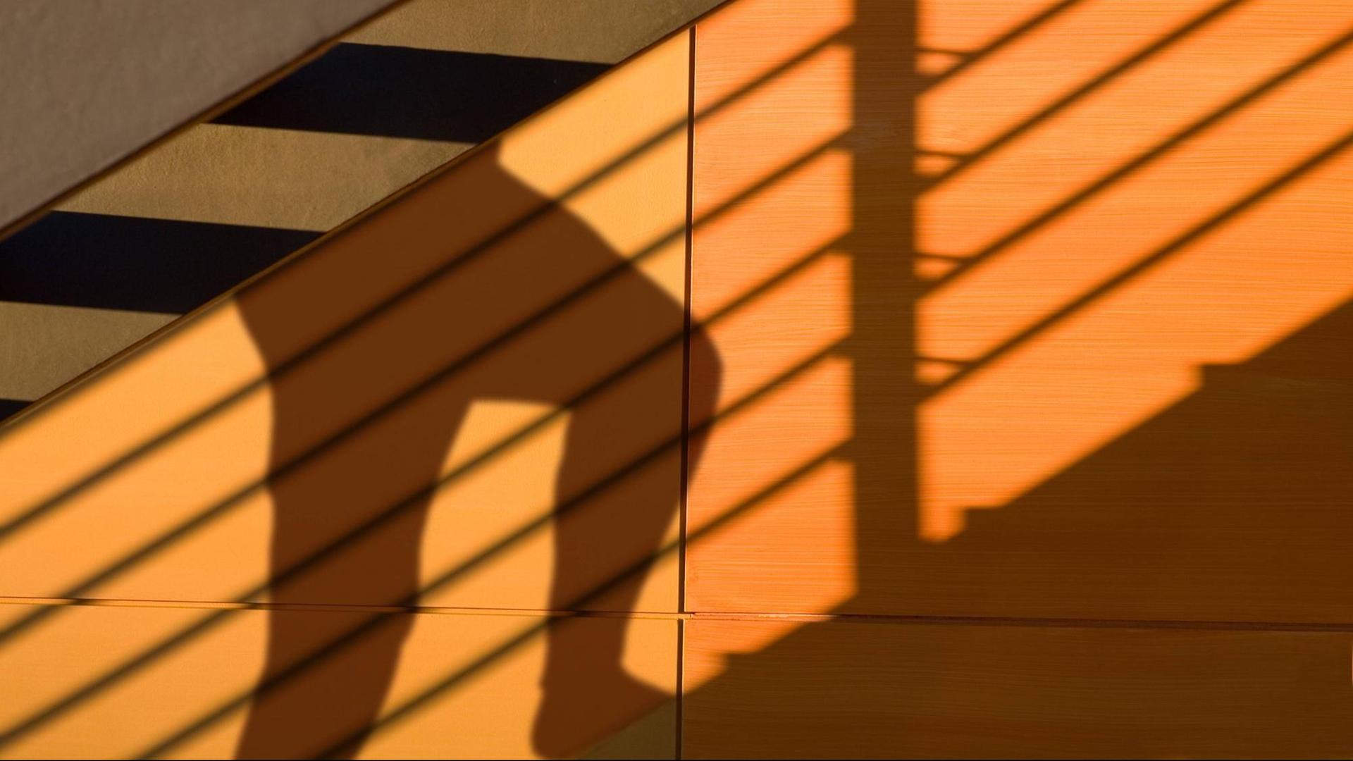 Jemand steigt eine Treppe hinauf und wirft dabei Schatten Jemand steigt eine Treppe hinauf und wirft dabei Schatten