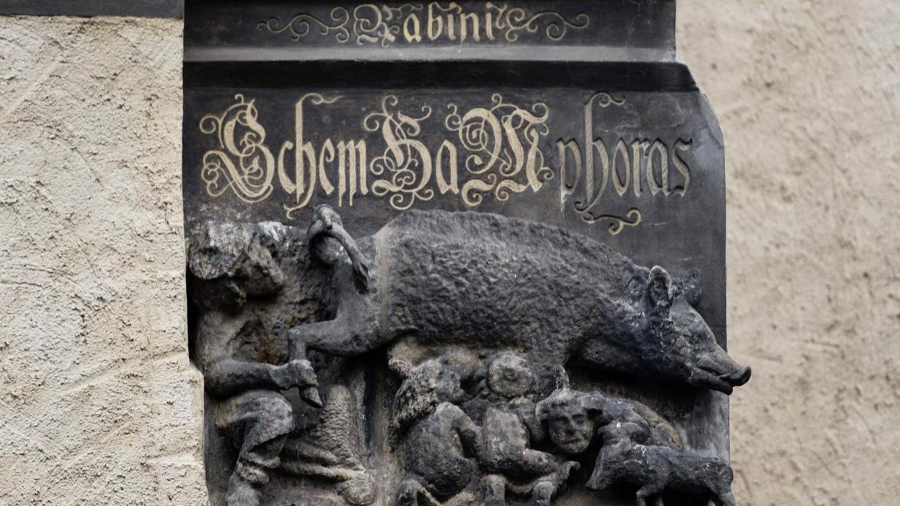 Die Mittelalterliche Judensau , ein Schmaeh- u. Spottbild auf die Juden, an der Stadtkirche St. Marien in der Lutherstadt Wittenberg. Die steinerne Skulptur zeigt eine Sau, an deren Zitzen sich Menschen laben.  