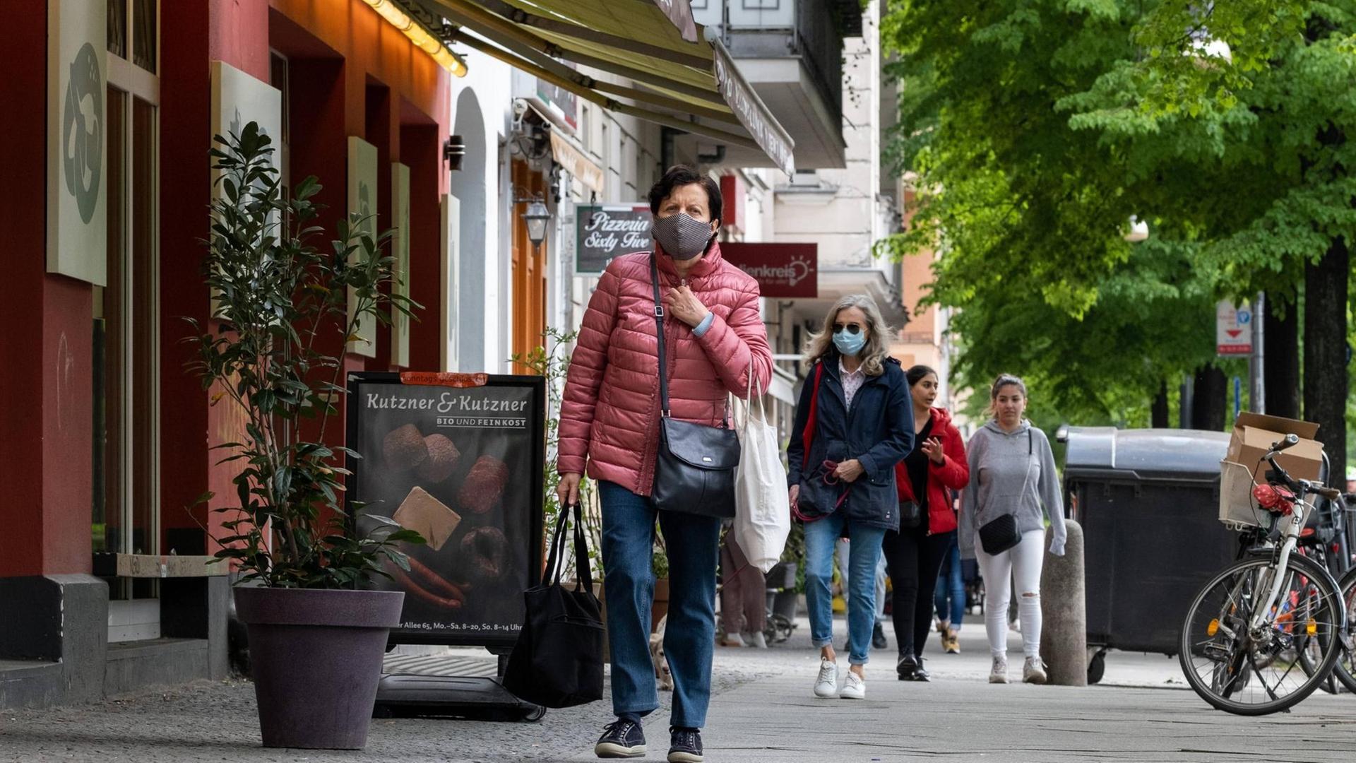 Frau mit Gesichtsmaske läuft auf Gehweg Frau mit Gesichtsmaske läuft auf Gehweg