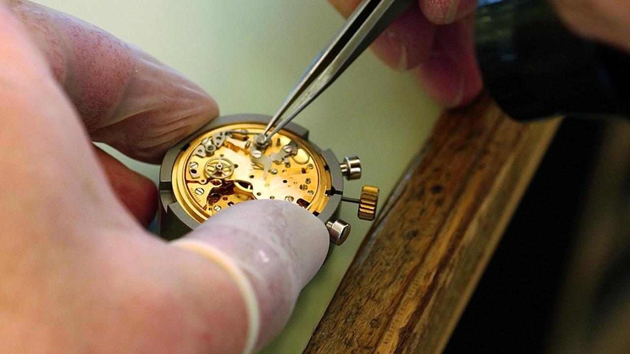 Ein Uhrmacher justiert die Teile des Uhrwerks für eine Armbanduhr, aufgenommen in der Omega-Manufaktur in Biel in der Schweiz. Ein Uhrmacher justiert die Teile des Uhrwerks für eine Armbanduhr, aufgenommen in der Omega-Manufaktur in Biel in der Schweiz.