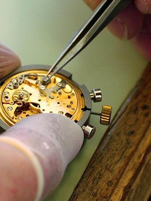 Ein Uhrmacher justiert die Teile des Uhrwerks für eine Armbanduhr, aufgenommen in der Omega-Manufaktur in Biel in der Schweiz.