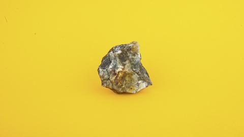 Ein Arsen-Stein fotografiert auf gelbem Hintergrund.