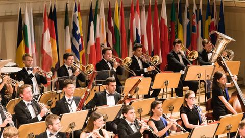 Hinter den Musikern des Orchester sind viele Fahnen der EU-Länder aufgestellt.