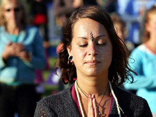Eine Frau steht in Berlin beim Yogafestival in der Danksagungshaltung "Namaste".