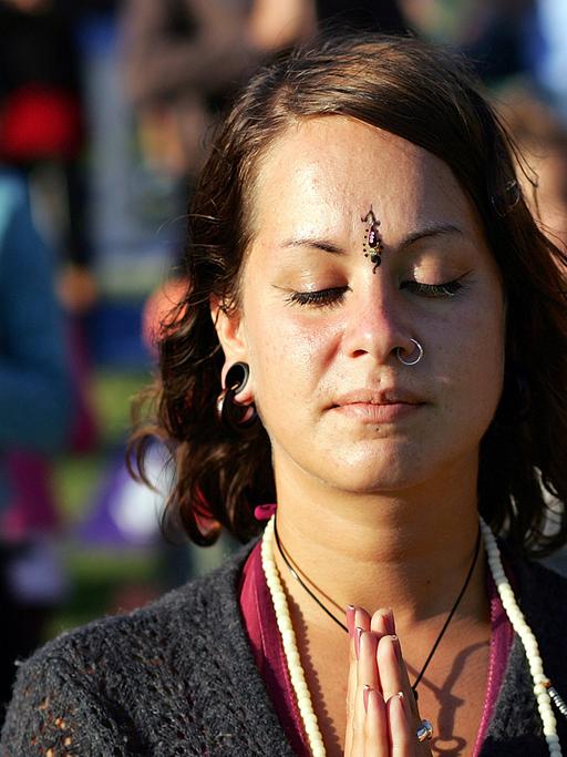 Eine Frau steht in Berlin beim Yogafestival in der Danksagungshaltung "Namaste".