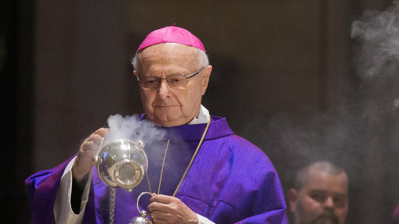 Robert Zollitsch schwenkt in violettem Ornat mit roter Kappe ein Weihrauchfass am Altar