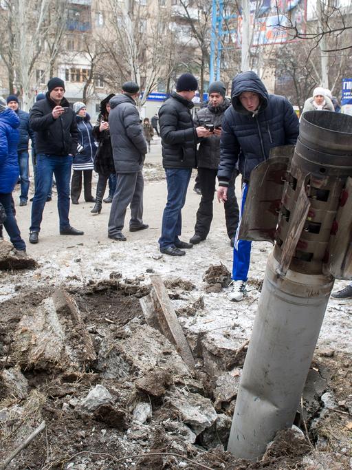Nach dem Einschlag einer Rakete in der Stadt Kramatorsk versammeln sich viele Zivilisten um den Krater.