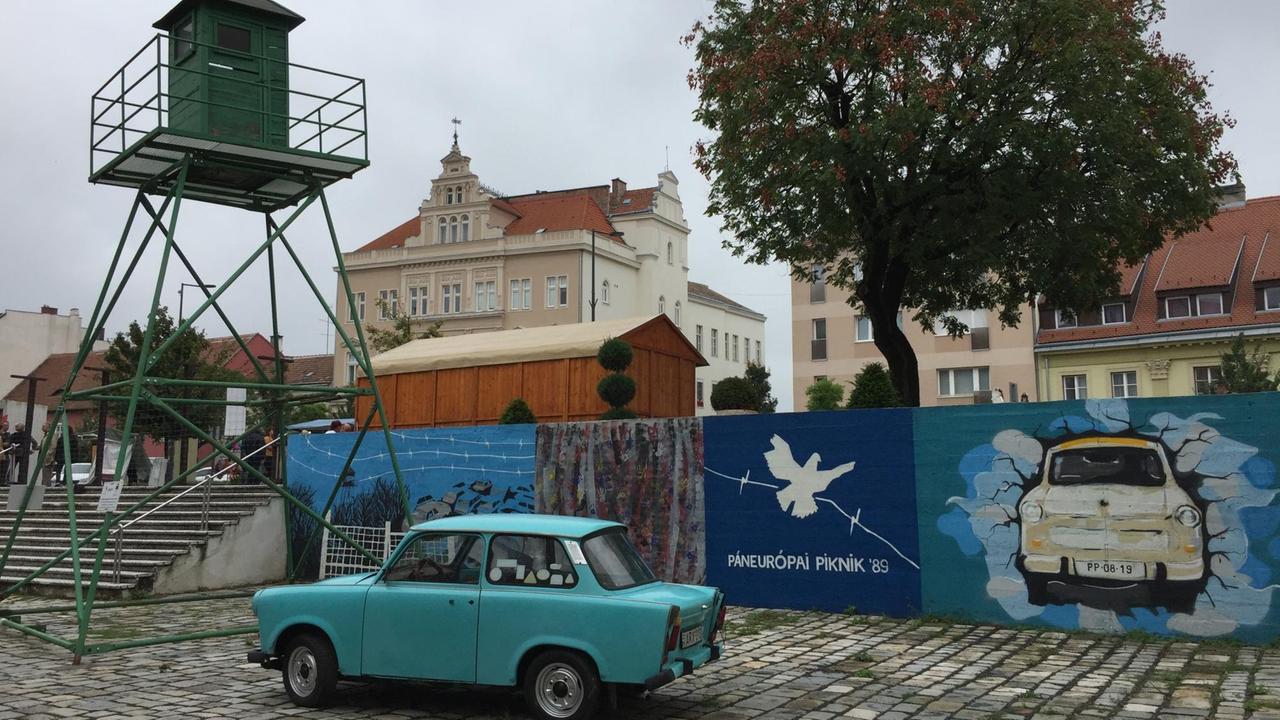 In Soprons Innenstadt gibt es einen kleine Freiluft-Ausstellung: Ein Wachturm steht da, ein Trabant und das Original-Tor durch den Eisernen Vorhang In Soprons Innenstadt gibt es einen kleine Freiluft-Ausstellung: Ein Wachturm steht da, ein Trabant und das Original-Tor durch den Eisernen Vorhang