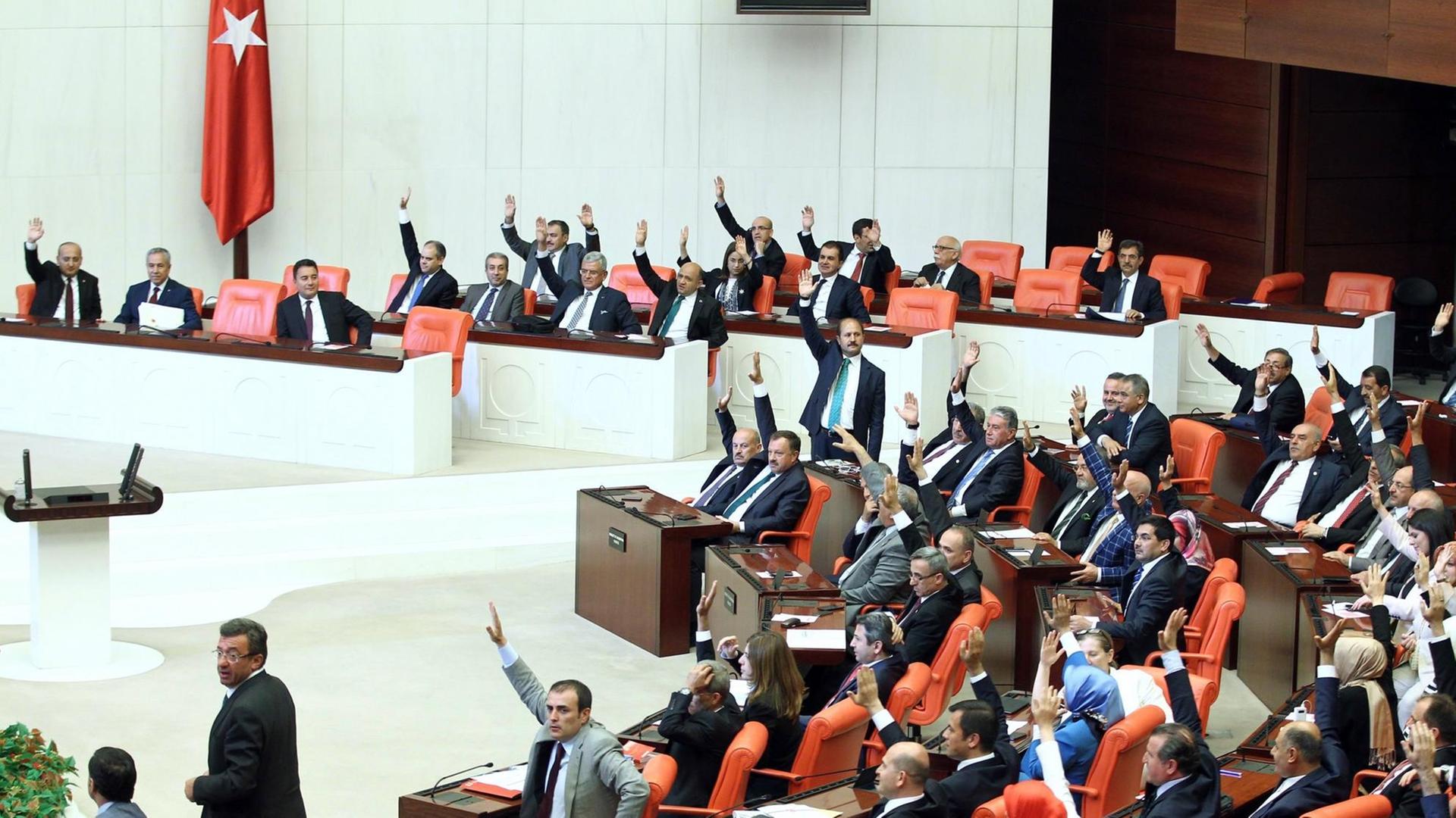 Viele Abgeordnete im Parlament in Ankara heben bei einer Abstimmung die Hand.