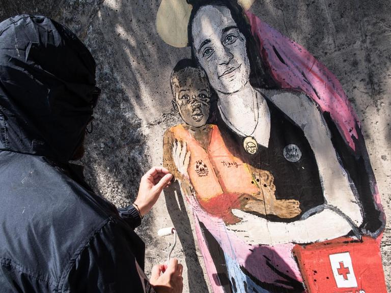 Der Street-Artist TVBOY malt sein Graffiti von Carola Rackete als Marienfigur an eine Wand in der sizilianischen Hafenstadt Taormina.