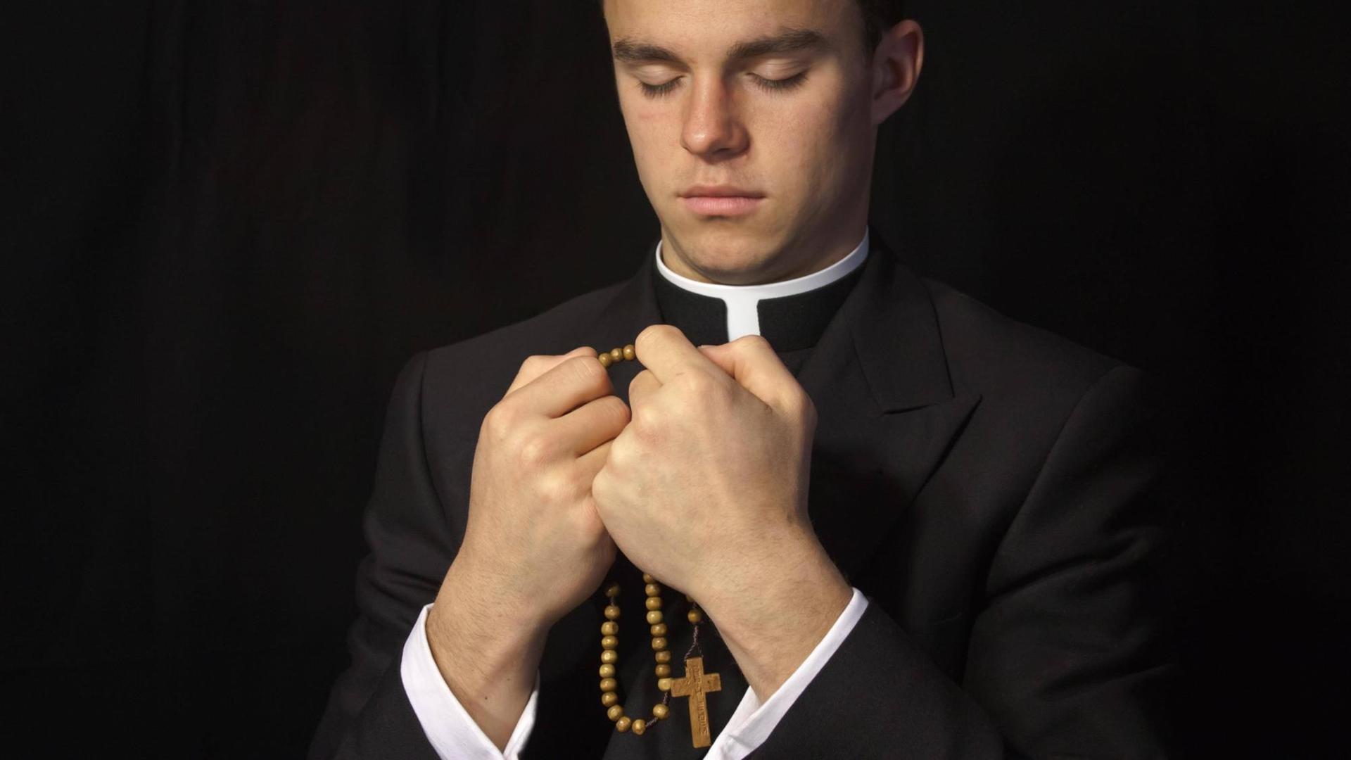 Junger Priester mit geschlossenen Augen, in den Händen einen Rosenkranz. Junger Priester mit geschlossenen Augen, in den Händen einen Rosenkranz.