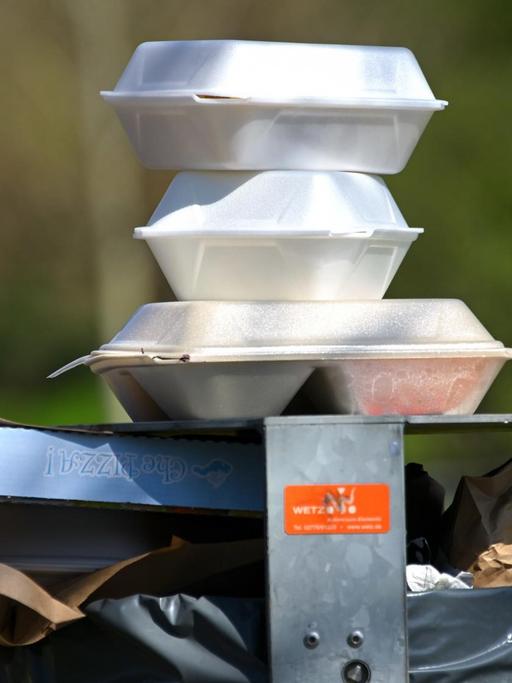 Leere Speise-Verpackungen stapeln sich im Nordstadtpark in Kassel auf einem Mülleimer.