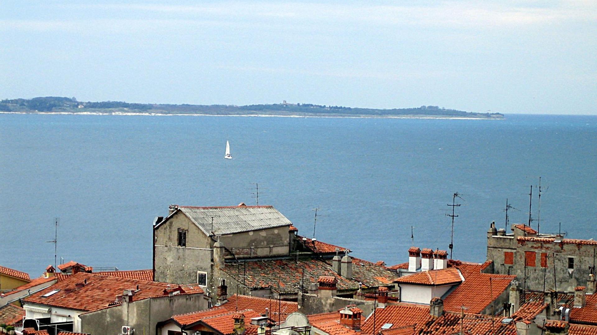 Blick auf die Bucht vom slowenischen Piran aus, dessen Häuser im Vordergrund zu sehen sind. Hinten ist die kroatische Küste der Halbinsel Istrien zu erkennen. Blick auf die Bucht vom slowenischen Piran aus, dessen Häuser im Vordergrund zu sehen sind. Hinten ist die kroatische Küste der Halbinsel Istrien zu erkennen.
