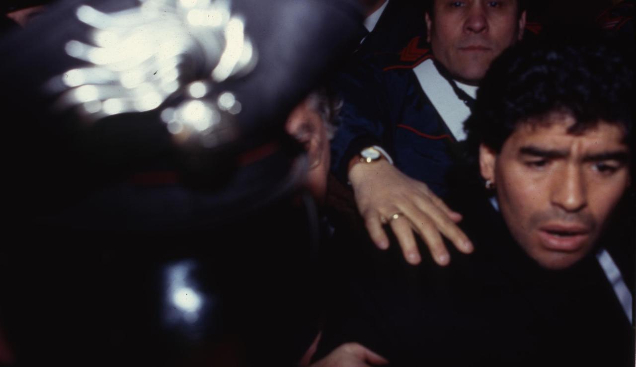 Diego Maradona verlässt das Tribunal von Neapel 1991. Er wird von Security begleitet und drängt sich durch ein Blitzlichtgewitter. Diego Maradona verlässt das Tribunal von Neapel 1991. Er wird von Security begleitet und drängt sich durch ein Blitzlichtgewitter.