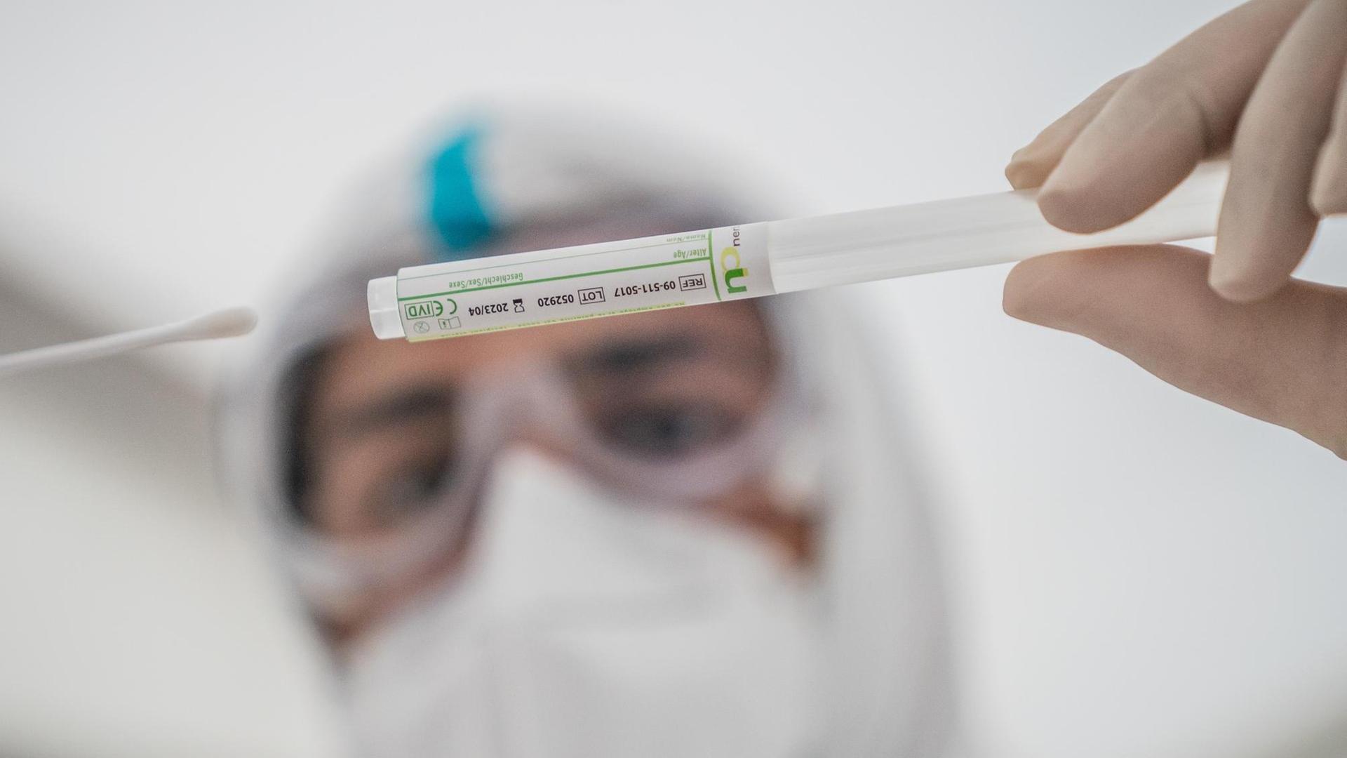 Ein Mitglied des medizinischen Personals steckt ein Wattestäbchen nach einem PCR-Abstrich zum Test auf COVID-19 in ein Röhrchen. Ein Mitglied des medizinischen Personals steckt ein Wattestäbchen nach einem PCR-Abstrich zum Test auf COVID-19 in ein Röhrchen.