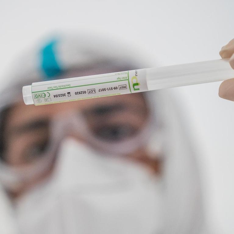 Ein Mitglied des medizinischen Personals steckt ein Wattestäbchen nach einem PCR-Abstrich zum Test auf COVID-19 in ein Röhrchen.
