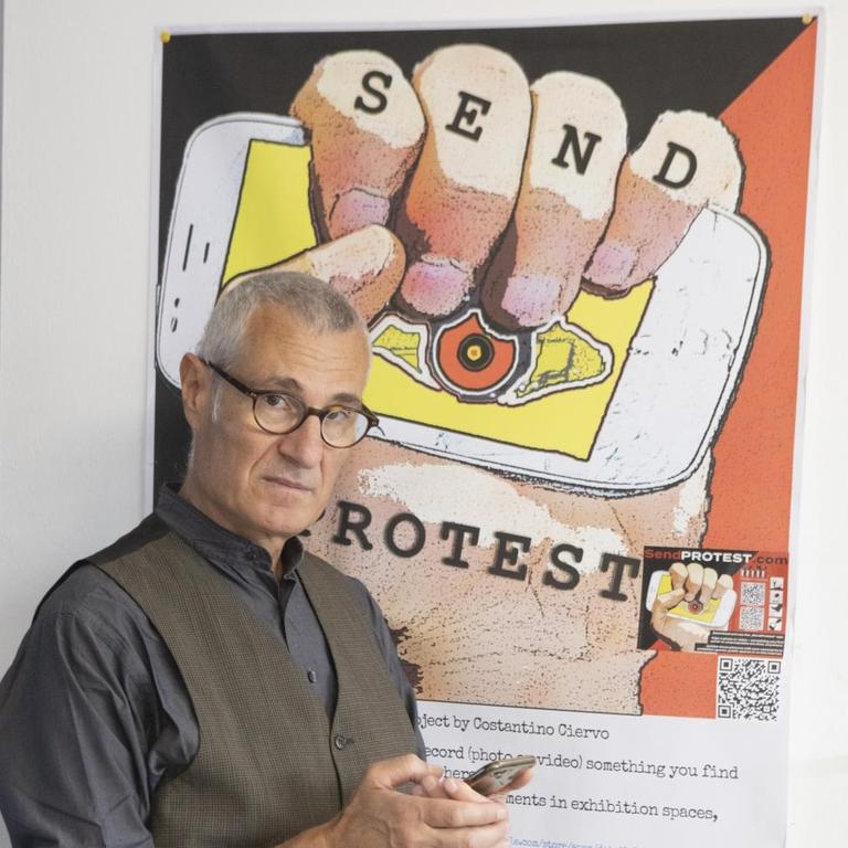 Costantino Ciervo steht vor einem Plakat mit der Aufschrift "Send Protest". Costantino Ciervo steht vor einem Plakat mit der Aufschrift "Send Protest".