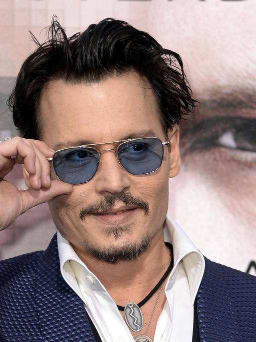 Hauptdarsteller Johnny Depp steht bei der Premiere von "Transcendence" in Westwood, Kalifornien, mit Sonnenbrille vor einem Filmplakat.