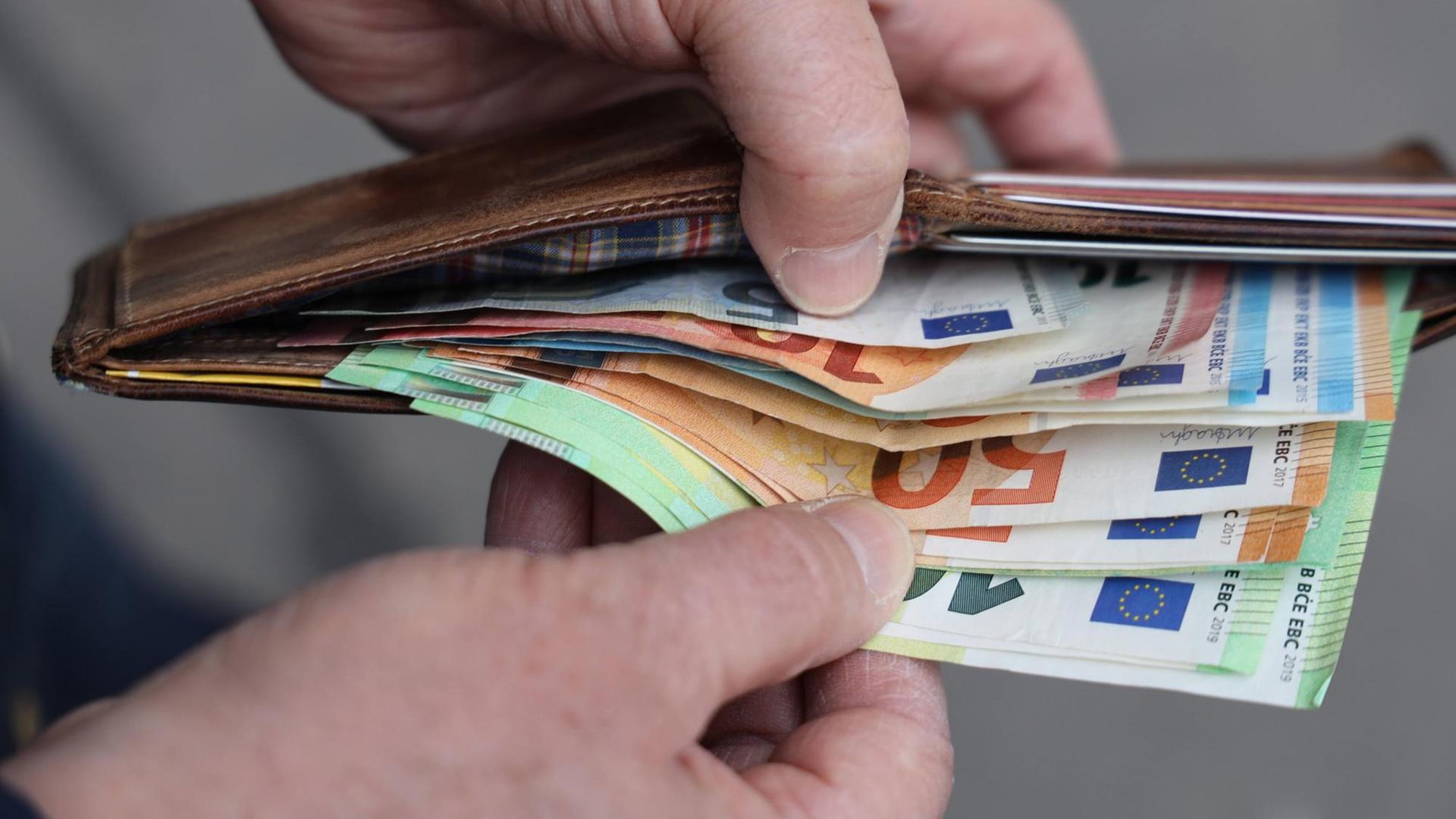 Hände halten eine Geldbörse mit Euroscheinen auf Hände halten eine Geldbörse mit Euroscheinen auf