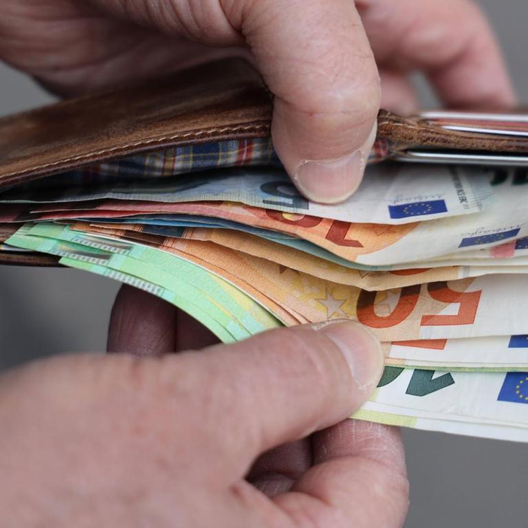 Hände halten eine Geldbörse mit Euroscheinen auf