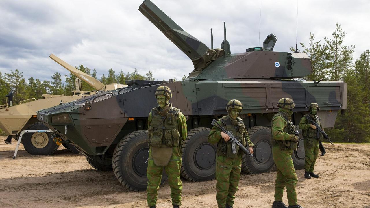 Finnische Soldaten vor einem Patria-Panzer