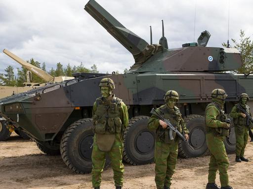 Finnische Soldaten vor einem Patria-Panzer