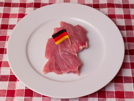 Ein Stück Schweinefleisch, geschnitten wie der Umriss von Deutschland und mit einer kleinen Deutschlandfahne