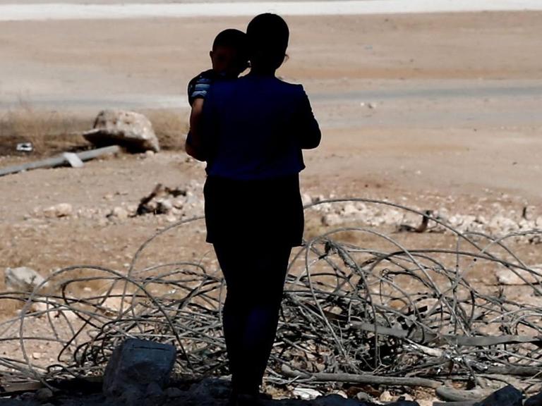Eine Frau mit ihrem Kind im zerstörten Kobane (Syrien).