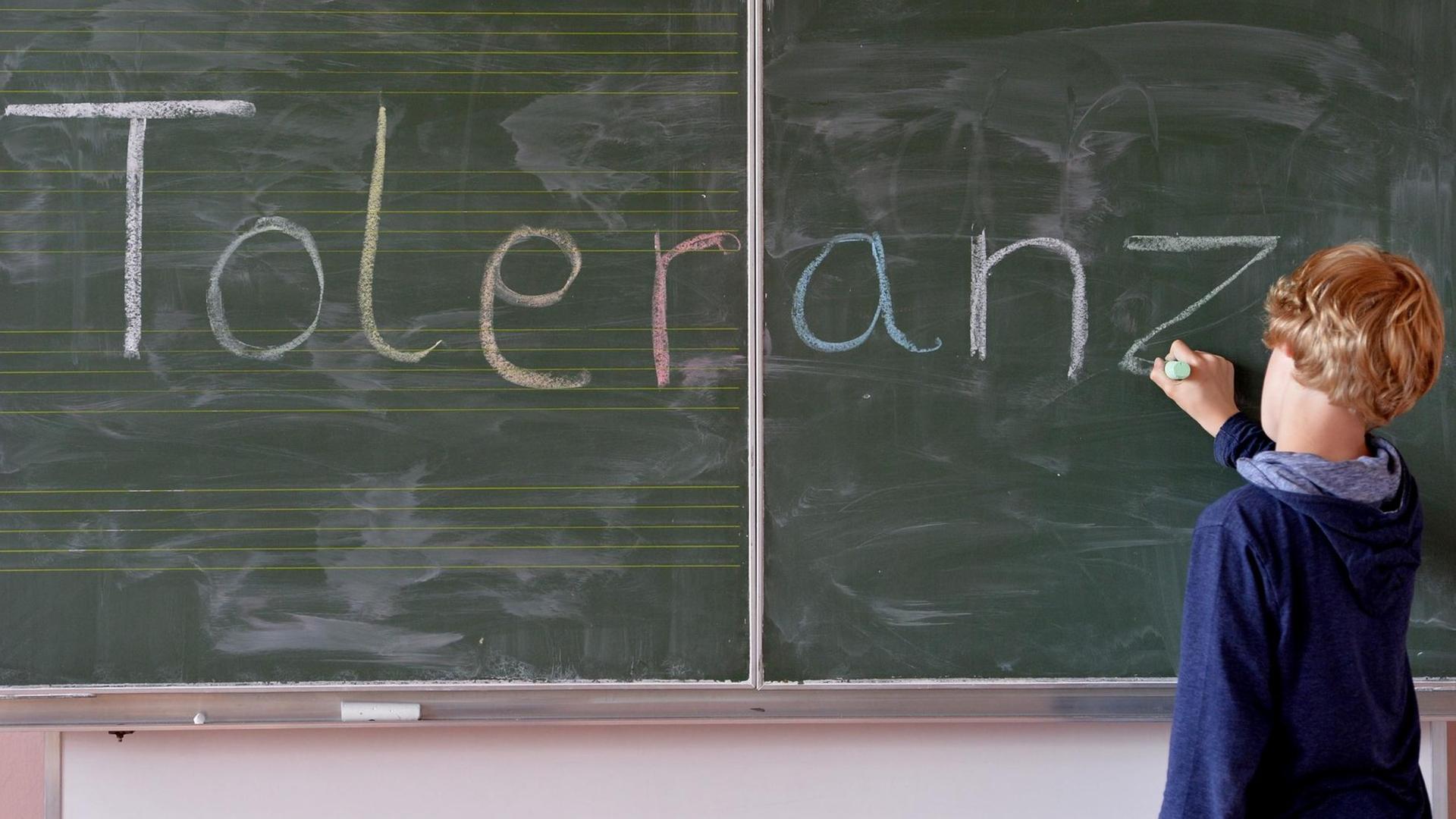 "Toleranz" schreibt ein Junge an die Tafel "Toleranz" schreibt ein Junge an die Tafel
