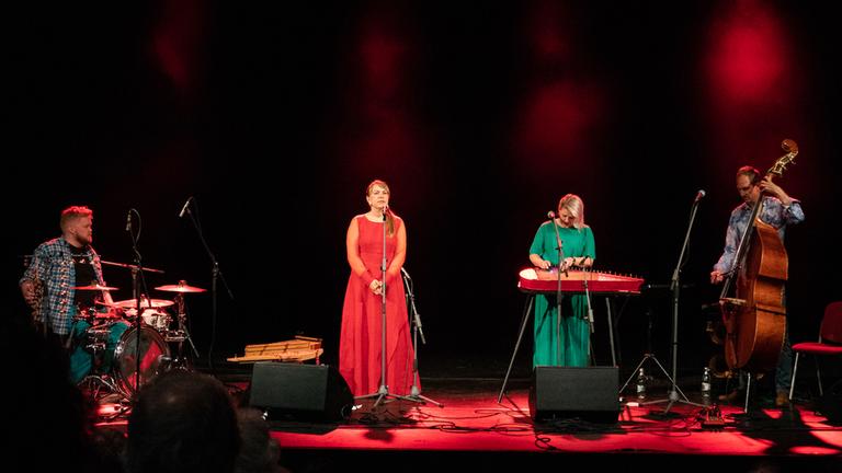 Mari Kalkun und die Musiker von Runorum stehen auf einer rot beleuchten Bühne