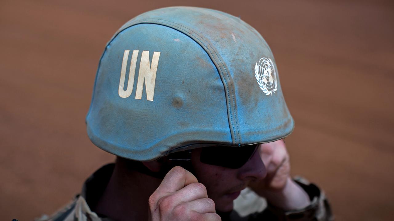 Ein Bundeswehrsoldat setzt sich im Camp Castor in Gao in Mali den Helm mit dem Logo der Vereinten Nationen auf.