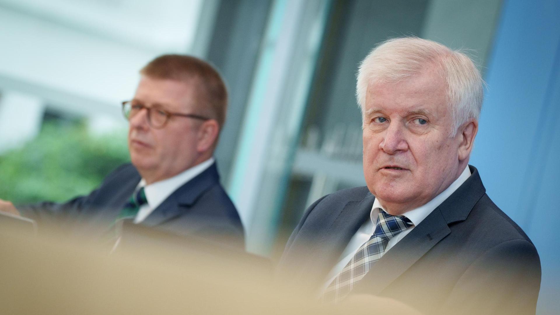 Haldenwang und Seehofer sitzen in der Bundes-Presse-Konferenz und stellen den Bericht vor. Haldenwang und Seehofer sitzen in der Bundes-Presse-Konferenz und stellen den Bericht vor.