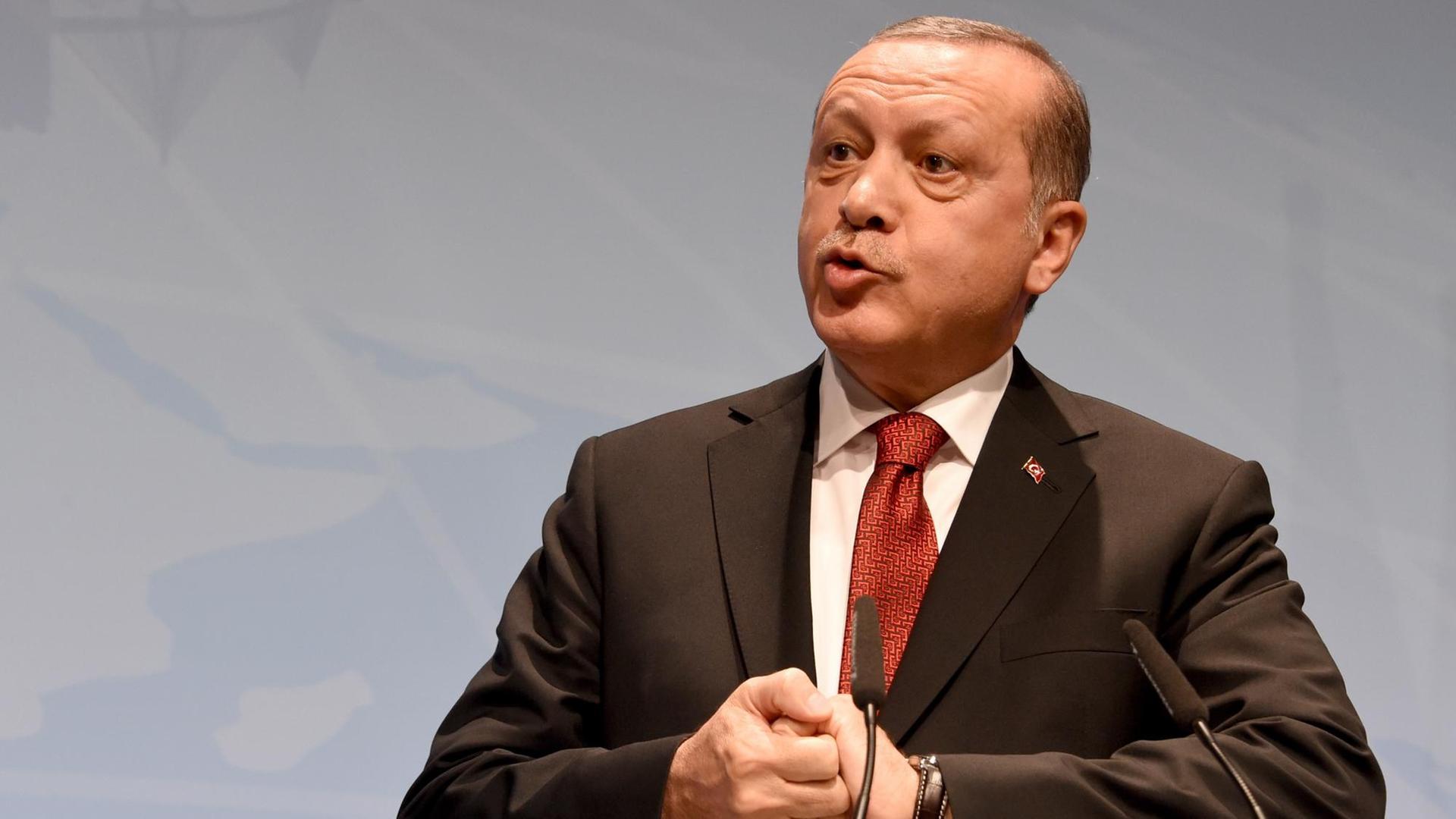 Erdogan spricht auf einer Bühne, seine Hände sind verschränkt.