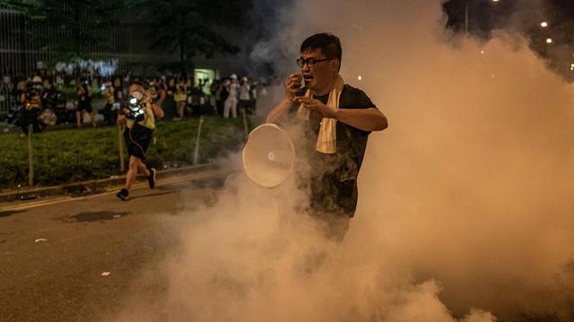 Ein Demonstrant mit Megafon läuft durch eine Tränengaswolke.