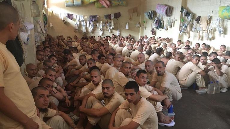 Häftlinge hocken in Reihen auf dem Boden