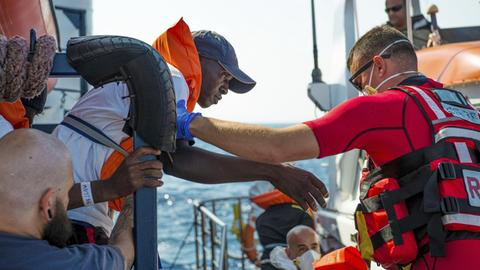 Ein Mann wird von der Seenotrettung SEA EYE vor der Küste von Libyen im Mittelmeer an Bord des Schiffes geholt, 2019.