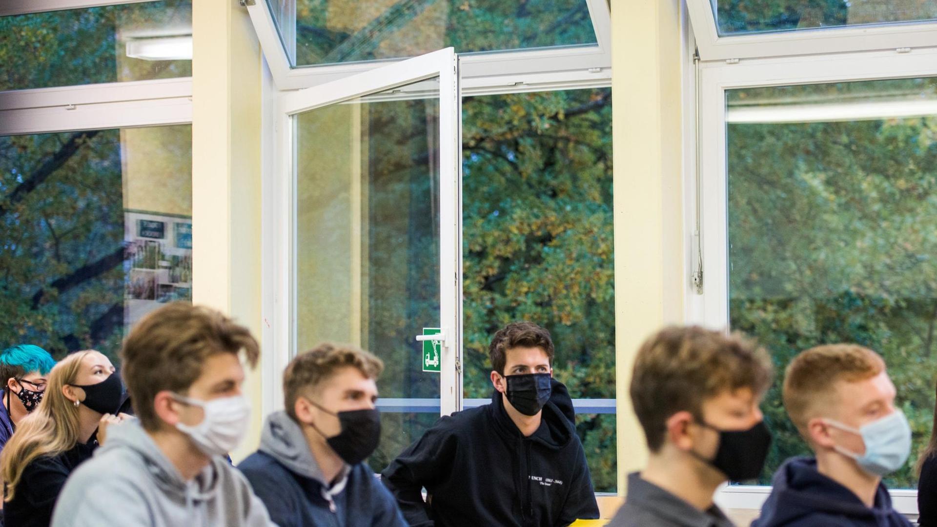 Schüler einer 13. Klasse der Oberstufe sitzen mit Masken im Deutsch-Unterricht vor einem geöffneten Fenster. Schüler einer 13. Klasse der Oberstufe sitzen mit Masken im Deutsch-Unterricht vor einem geöffneten Fenster.